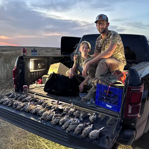 Father and son pictured with harvested doves on bed of truck.