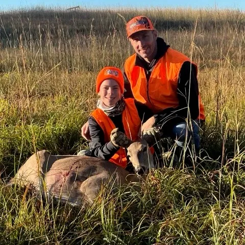 Father and son are pictured with the harvested deer.