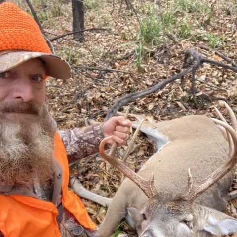 Hunter wearing orange pictured with a harvested deer.