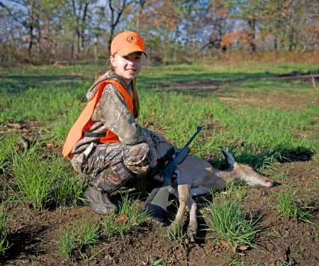 Girl with harvested doe in the field.