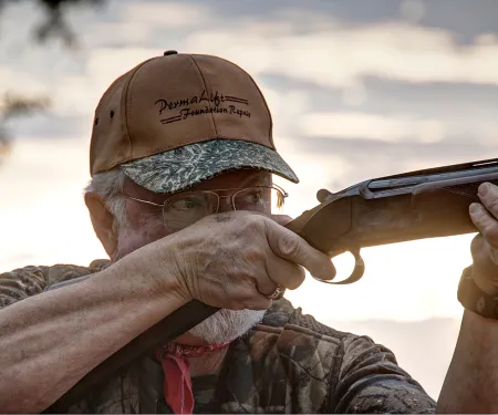 A man holds a shotgun. 