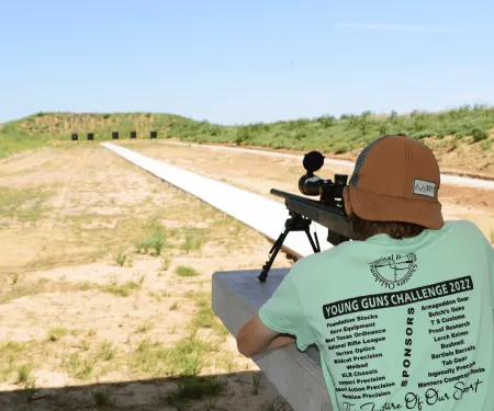 A male teenager is photographed from behind as he aims his rifle down the Packsaddle WMA shooting range.