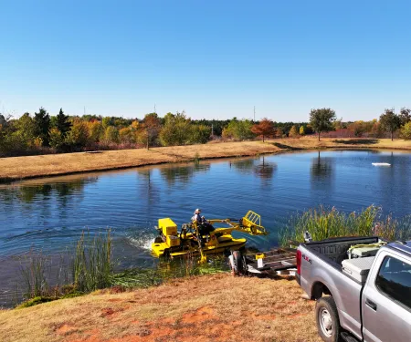 A fisheries employee of the Oklahoma Department of Wildlife Conservation is using a WeeDoo to maintain a Close To Home Fishing pond at Mitch Park.