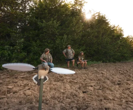 A photo of three women pictured behind a decoy dove. 