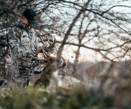 A bowhunter inspects the antlers of his harvested buck.