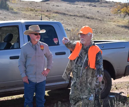 A biologist and a hunter have a conversation in the field. 