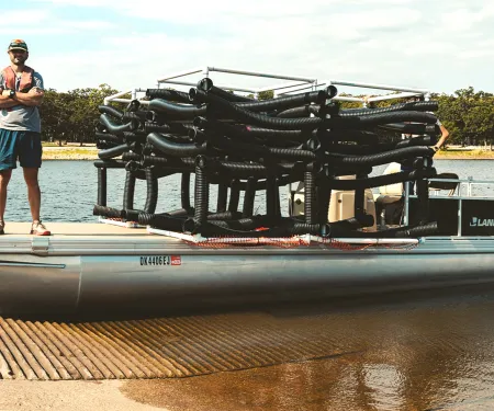 An Oklahoma Wildlife Department employee standing next to artificial fish habitat.