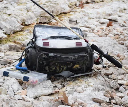A tackle box, tackle bag, and fishing pole sitting together. 