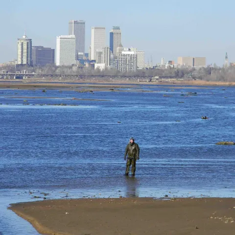 Biologist stands in Arkansas River near downtown Tulsa.