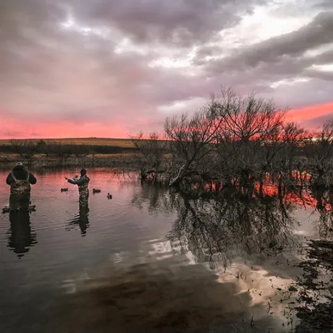 Duck hunters stand in a pool of water setting out decoys. Photo by Sarah Southerland