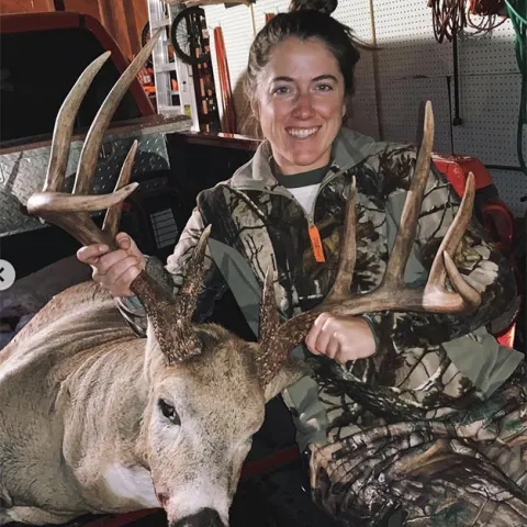 Allyssa Brown with harvested buck in a garage in the bed of a truck.