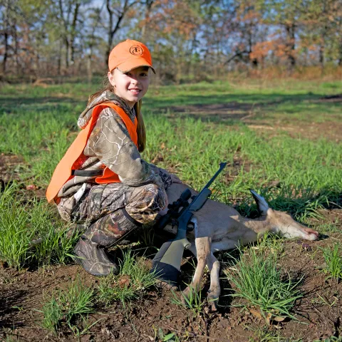 Girl with harvested doe in the field.