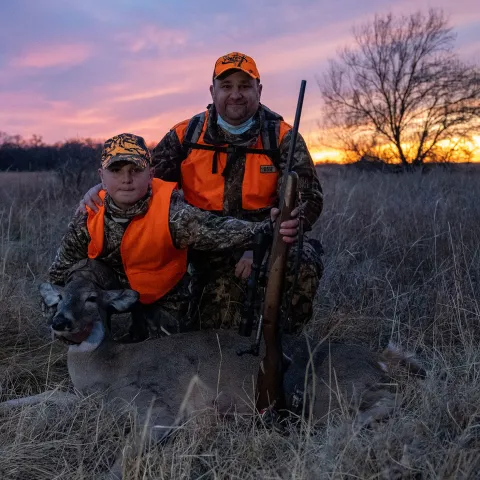 Father and son in the field with harvested doe, photo by Smokey Solis