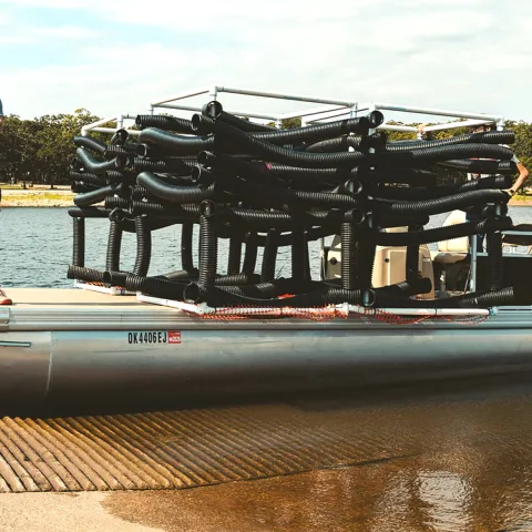 An Oklahoma Wildlife Department employee standing next to artificial fish habitat.