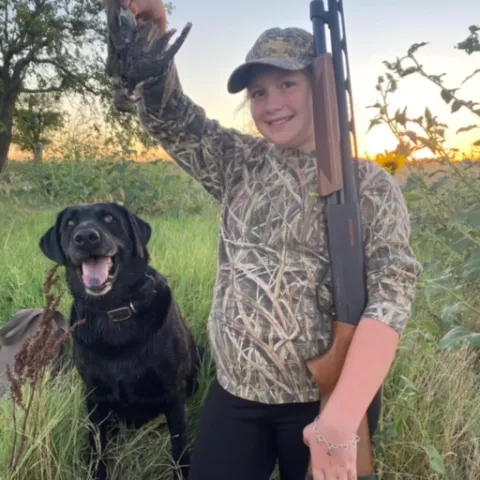 Girl hunted with dog with the dove she harvested.