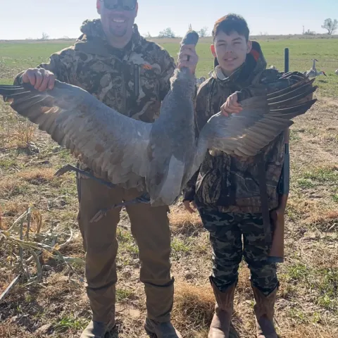 dad and son with harvested sandhill crane