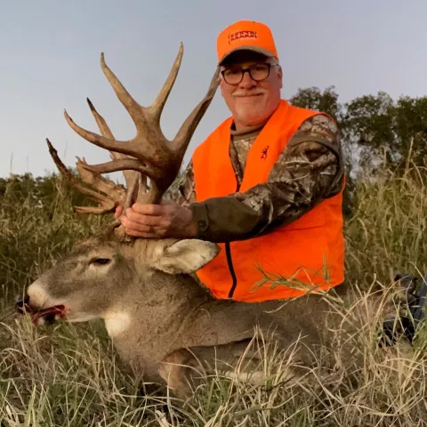 Hunter wearing orange pictured with a harvested deer.