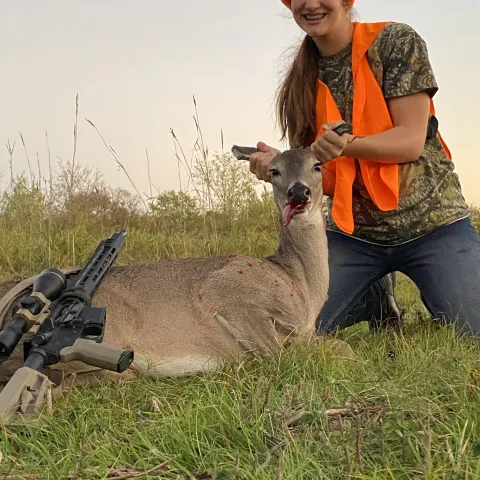 Young hunter wearing orange pictured with his first buck.