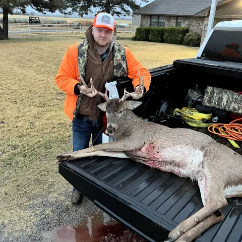 Hunter holding the head up of a harvested deer sitting on the 
