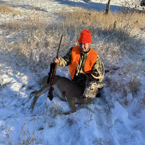 Hunter is pictured with harvested deer in snow.