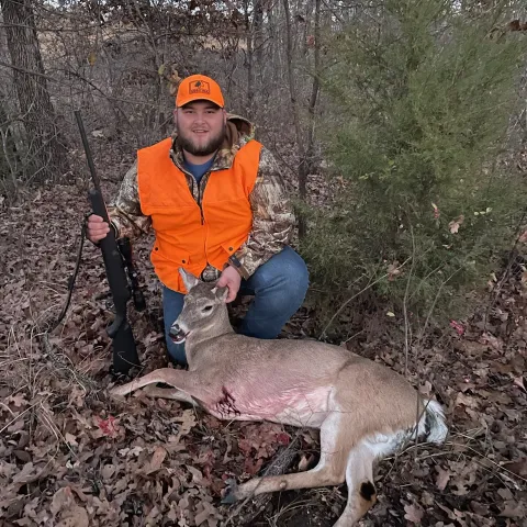 Hunter wearing orange pictured with his first harvested deer.