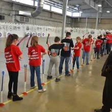 USFWS employee assisting at a Oklahoma National Archery in the Schools Program shoot, with students on the line.