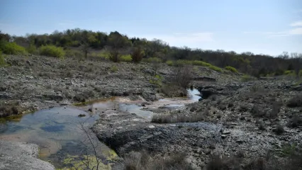A rocky hillside with a stream flowing in the foreground.
