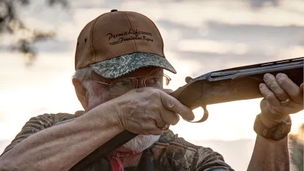 A man holds a shotgun. 