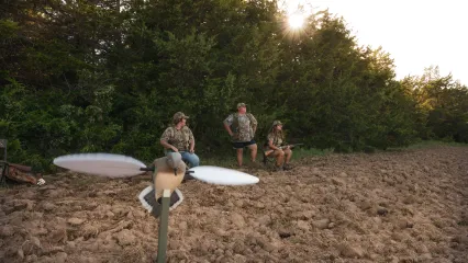 A photo of three women pictured behind a decoy dove. 