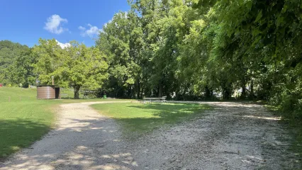 Public access point at Echota Fishing Area featuring a gravel road, shaded picnic tables, and restroom facilities beneath a canopy of mature trees.