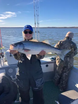 Woman holding a large striped bass.