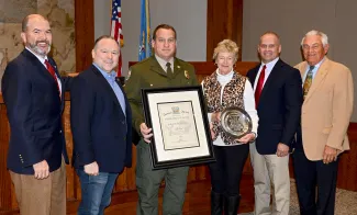 Gathered for the presentation of the 2018 Oklahoma Wildlife Officer of the Year Award from Shikar-Safari Club International are, from left, Oklahoma Wildlife Department Director J.D. Strong, Raegen Siegfried of Shikar-Safari Club, Game Warden Jay Harvey, Suzie Brewster of Shikar-Safari Club, Department Assistant Chief of Law Enforcement Nathan Erdman, and Wildlife Conservation Commissioner Bill Brewster of Shikar-Safari Club. (Don P. Brown/ODWC)