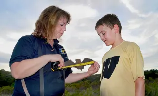 Wildlife biologist Melynda Hickman uses a model of a bat to educate a youngster during a Selman Bat Watch program. Hickman was named 2018 Wildlife Biologist of the Year by the Southeastern Association of Fish and Wildlife Agencies. (Blake Podhajsky/ODWC)