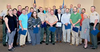 Oklahoma Wildlife Conservation Commissioners and the Wildlife Department Director, back row, recognize the 2018 graduates of the Department's two-year Wildlife Resources Professional program.