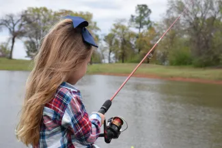 Girl holding a spinning rod while fishing.
