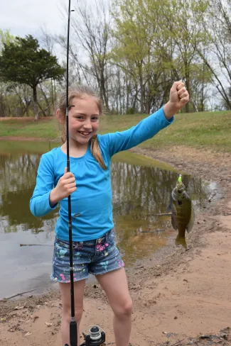 Girl holding a sunfish on the end of the line.
