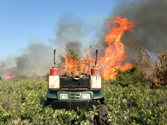A four-wheeler sits in front of flames. 