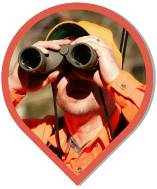 A close-up of a hunter looking through binoculars, cropped in the shape of a map icon.