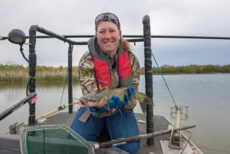 A biologist is smiling holding a channel catfish.