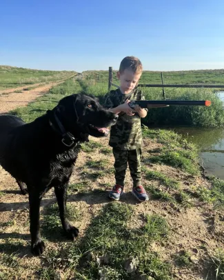 lab standing with a little boy while hunting