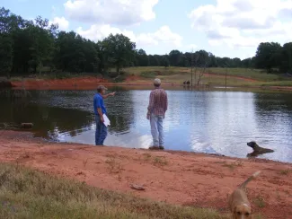 An ODWC biologist and landowner are overlooking a pond on private property.
