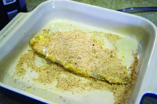 A fish filet is covered in bread crumbs.