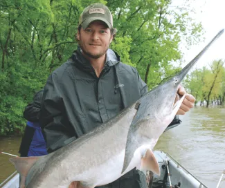 Blake Shelton holds a paddlefish he caught.