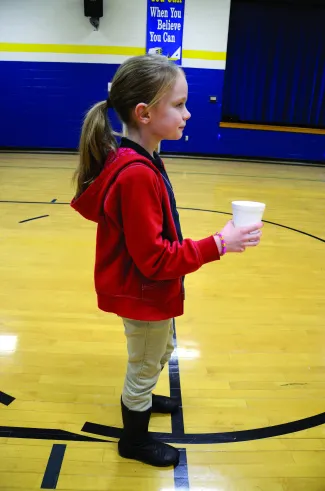 A girl practicing casting with a cup of water. 