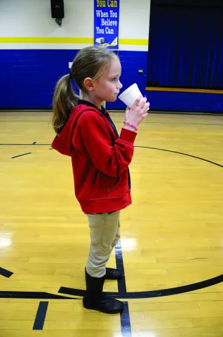 A girl practicing casting with a cup of water. 