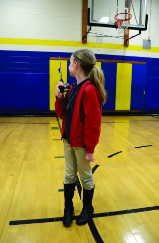A girl holding a spincast rod/reel. 
