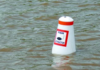 A white and orange buoy says "Fish Attractor" with a black icon of a hook in front of a fish.