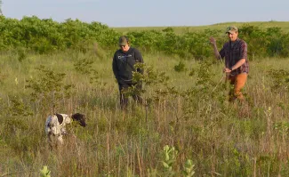 2 male hunters and 1 hunt dog in field