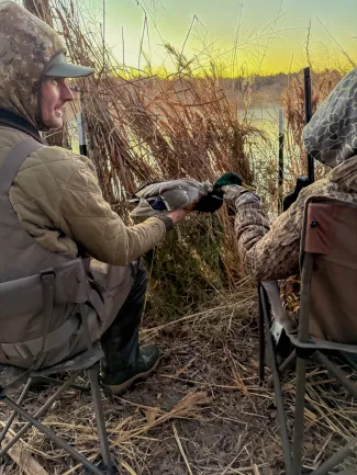man handing a duck to a young youth hunter