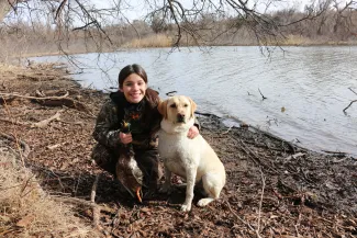 young girl holding ducks and sitting with a labrador retriever dog 